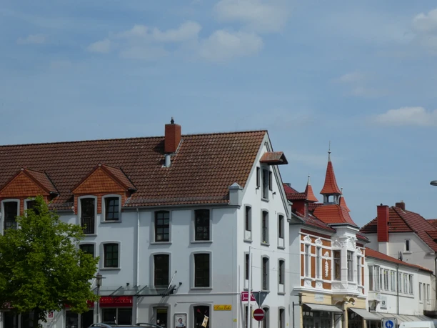 Speicher Scherf Historisches Backsteinhaus mit markantem Satteldach vor blauem Himmel in urbaner Umgebung.
