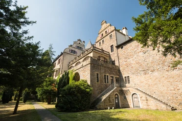 Gebäude Schloss Landsberg mit kleinem Weg und Bäumen. Historisches Schloss mit Treppe, umgeben von Bäumen und einem schmalen Weg, aufgenommen bei klarem Himmel.