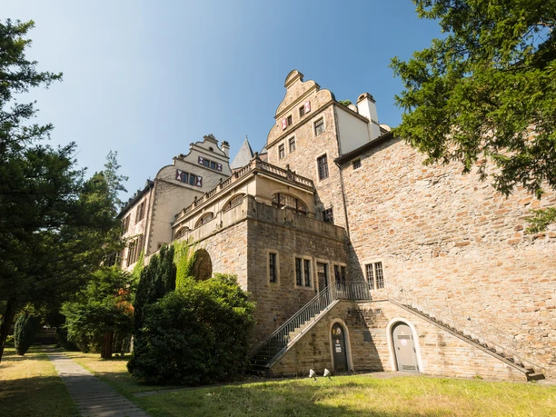 Gebäude Schloss Landsberg mit kleinem Weg und Bäumen. Historisches Schloss mit Treppe, umgeben von Bäumen und einem schmalen Weg, aufgenommen bei klarem Himmel.