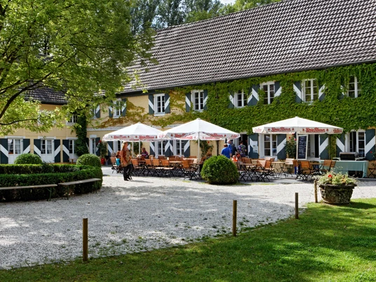 Gastronomie der Wasserburg Haus Graven in Langenfeld Sonniger Außenbereich der Wasserburg Haus Graven mit einladenden Sitzgelegenheiten und üppiger Begrünung.