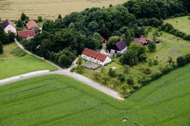 Heimathof Luftaufnahme.jpg Luftaufnahme eines Bauernhofes, umgeben von Feldern und Wald, einige Gebäude und ein Zugang zum Weg.