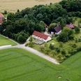 Heimathof Luftaufnahme.jpg Luftaufnahme eines Bauernhofes, umgeben von Feldern und Wald, einige Gebäude und ein Zugang zum Weg.
