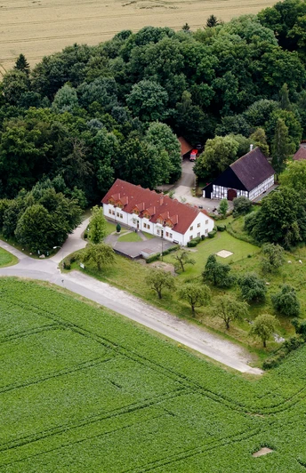 Heimathof Luftaufnahme.jpg Luftaufnahme eines Bauernhofes, umgeben von Feldern und Wald, einige Gebäude und ein Zugang zum Weg.