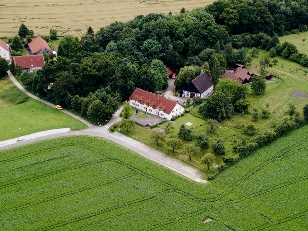Heimathof Luftaufnahme.jpg Luftaufnahme eines Bauernhofes, umgeben von Feldern und Wald, einige Gebäude und ein Zugang zum Weg.
