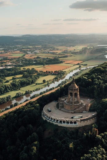 Porta-Westfalica-Kaiser-Wilhelm-Denkmal-Teutoburger-Wald-Tourismus-LeoThomas.jpg Kaiser-Wilhelm-Denkmal erhebt sich majestätisch auf einem bewaldeten Hügel, umgeben von Flusstälern.