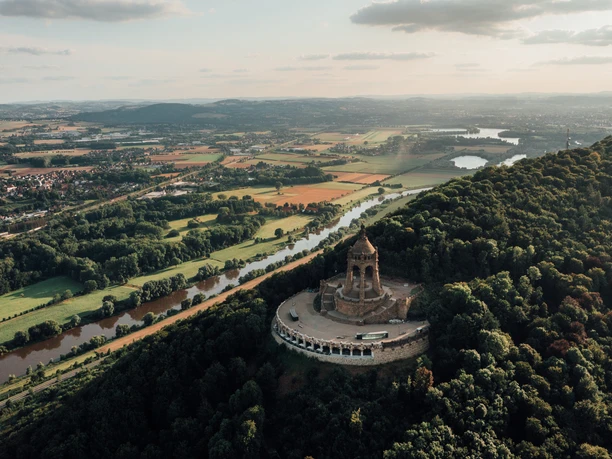 Porta-Westfalica-Kaiser-Wilhelm-Denkmal-Teutoburger-Wald-Tourismus-LeoThomas.jpg Kaiser-Wilhelm-Denkmal erhebt sich majestätisch auf einem bewaldeten Hügel, umgeben von Flusstälern.
