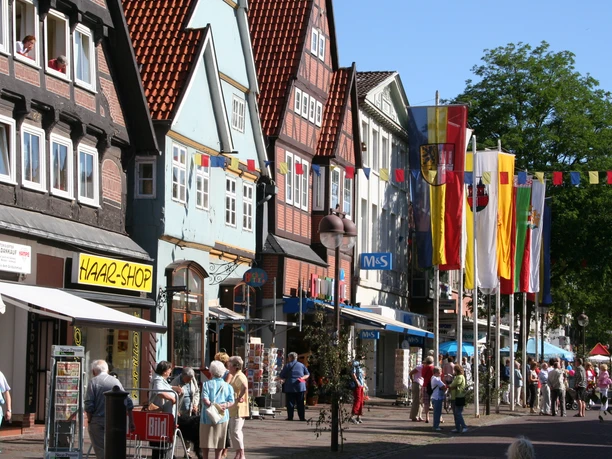 Altstadt Nienburg Lange Straße Fachwerkhäuser säumen die belebte Lange Straße in Nienburg, bunte Flaggen schmücken den blauen Himmel.