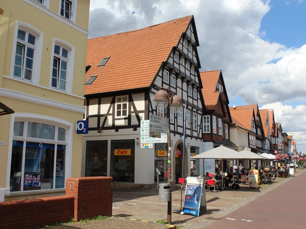 Patrizierhaus des Gödeke Schünemann Fachwerkhausreihe mit Terrassencafés auf einer belebten Fußgängerzone unter blauem Himmel.