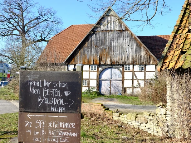 Kreuzung Lage Hagen Biohof Brinkmann.JPG Ein traditionelles Fachwerkgebäude in ländlicher Umgebung mit einem Schild über Bioprodukte.