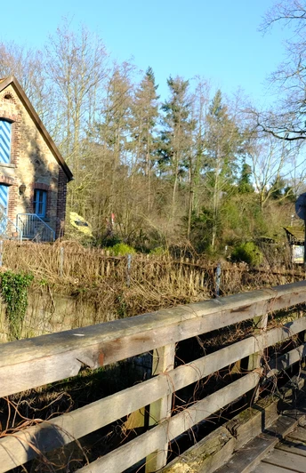 Fachwerkhaus mit Backsteinmauern, neben einem Holzzaun, im ländlichen Umfeld mit Fahrradständer.