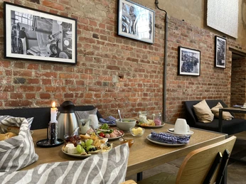 Frühstückstisch in historischer Fabrikatmosphäre mit Backsteinwand und Schwarzweißfotos an der Wand.