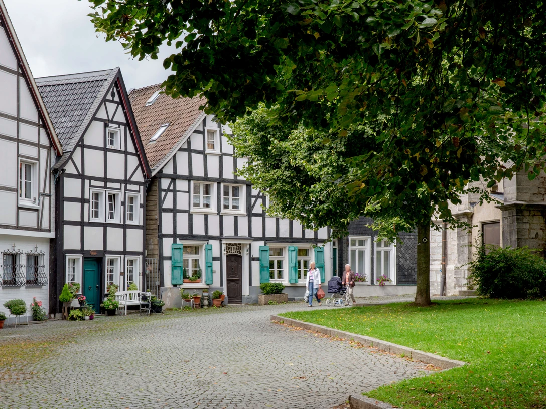Kirchplatz in der Wülfrather Altstadt Historischer Kirchplatz in Wülfrath mit Fachwerkhäusern und Kopfsteinpflaster, von Bäumen umgeben.