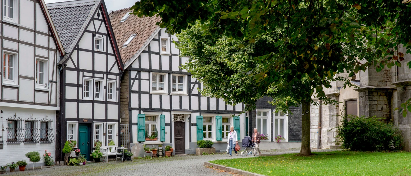 Kirchplatz in der Wülfrather Altstadt Historischer Kirchplatz in Wülfrath mit Fachwerkhäusern und Kopfsteinpflaster, von Bäumen umgeben.