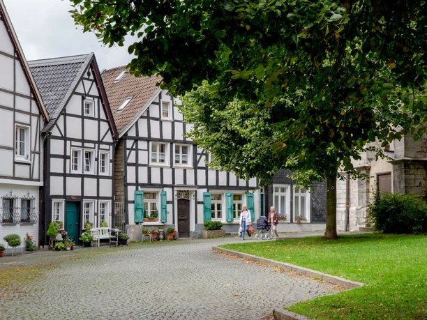 Kirchplatz in der Wülfrather Altstadt Historischer Kirchplatz in Wülfrath mit Fachwerkhäusern und Kopfsteinpflaster, von Bäumen umgeben.