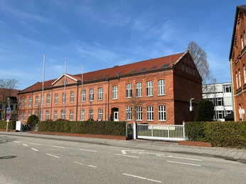 Historisches Gebäude der Polizeiakademie, leuchtend rote Backsteingestalt mit weißen Fensterrahmen.
