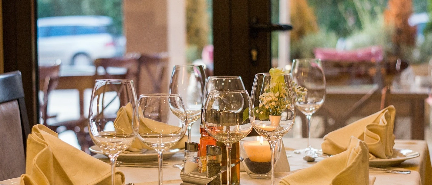 bottrop+restaurant-herzblut+bild01.jpg Ein elegant gedeckter Tisch mit weißen Stoffservietten und Gläsern in einem stilvollen Restaurant.