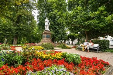 Denkmal umgeben von Blütenpracht