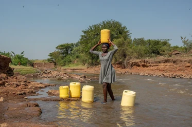 Mädchen holt Trinkwasser aus einem Fluß in der Näh