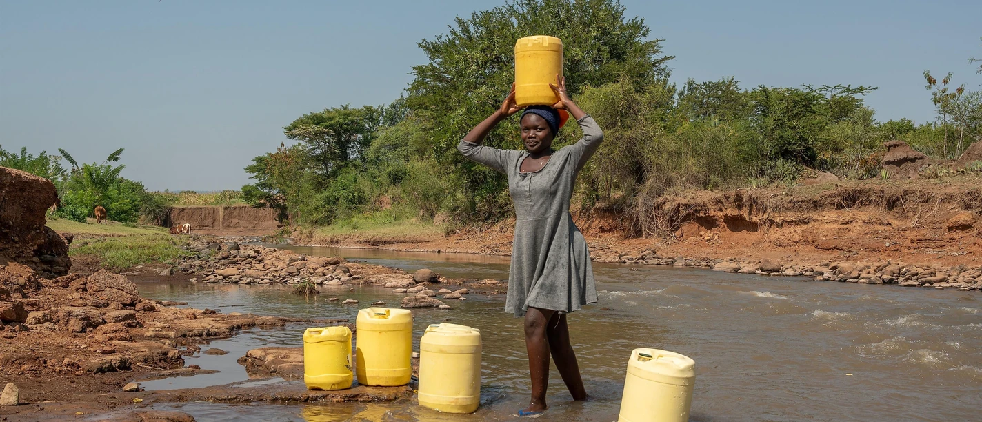 Mädchen holt Trinkwasser aus einem Fluß in der Näh