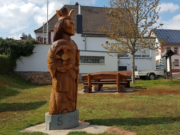 Zentrale Grünanlage mit Skulptur und Sitzgruppe