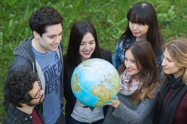 Studierende mit einem Globus in der Hand