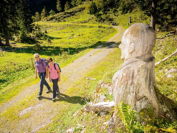 Wanderer auf dem Schnitzlerweg Axalp bei einer Skulptur