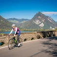 Une cycliste sur un vélo de route entre Interlaken et Spiez, en arrière-plan le lac de Thoune ainsi que le Harder