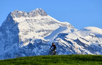 Biker unterwegs vor verschnietem Berg in der Region Aeschi