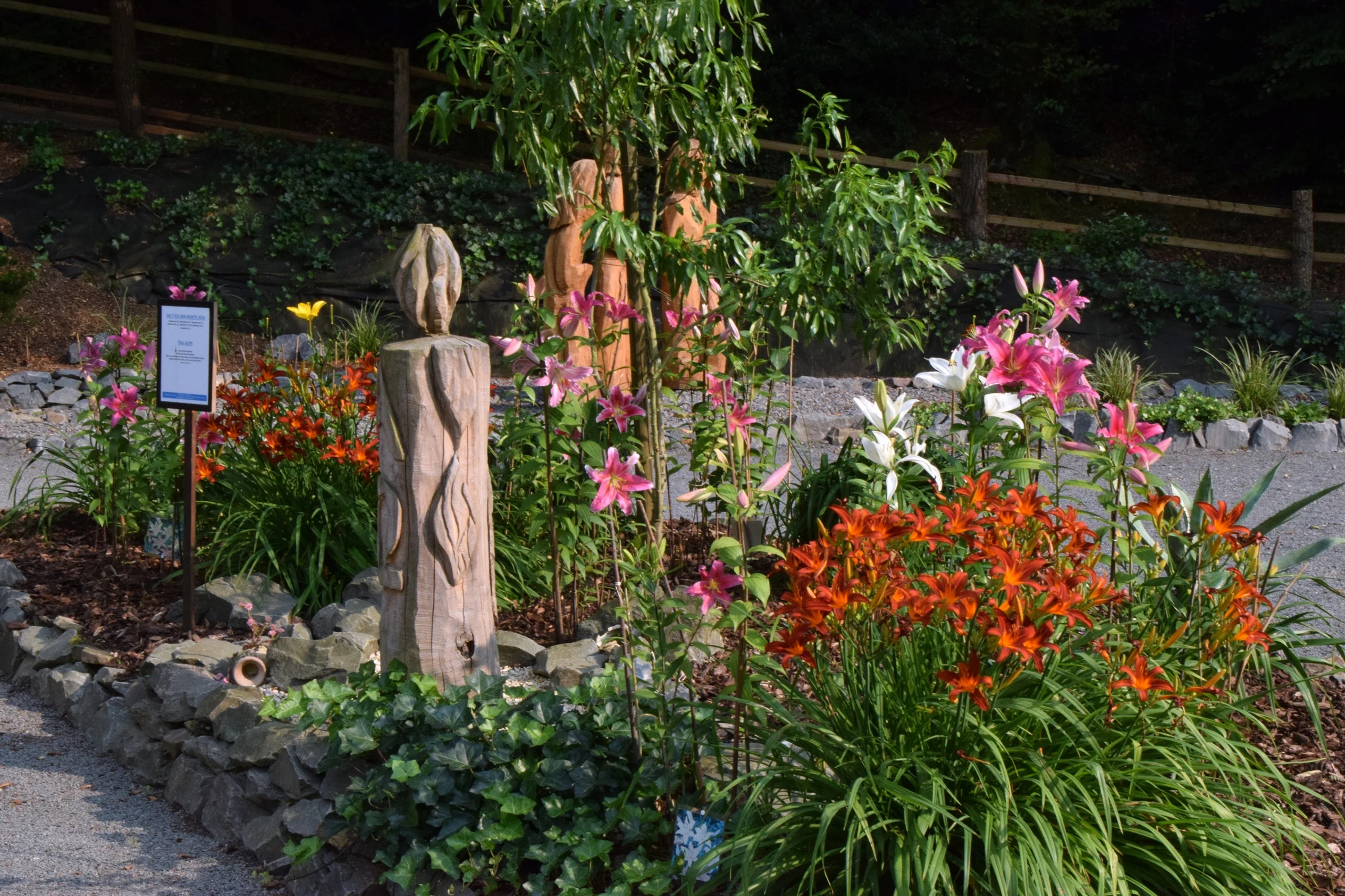 Künstlerische Holzfigur im bepflanzten Garten
