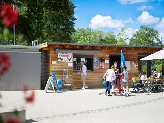 Monheim am Rhein'de Turist Danışma Giebner Ahşap kaplamalı, insan ve bisiklet turlarının olduğu, yeşil parkla çevrili turistik bilgilendirme.