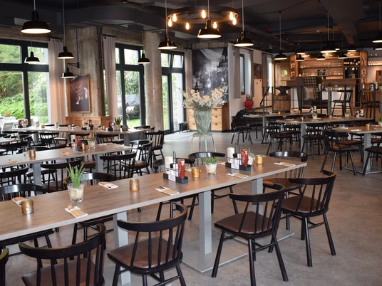 Restaurant Zur Gießerei in the Best Western plus Parkhotel Velbert Restaurant with modern wooden tables and dark chairs, surrounded by large windows and stylish lighting.