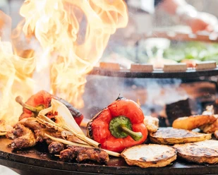 Monheim am Rhein'deki Marienburg'daki Grill Academy Kırmızı biber ve soğan gibi çeşitli sebzeler büyük bir ızgarada ateşte kavruluyor.