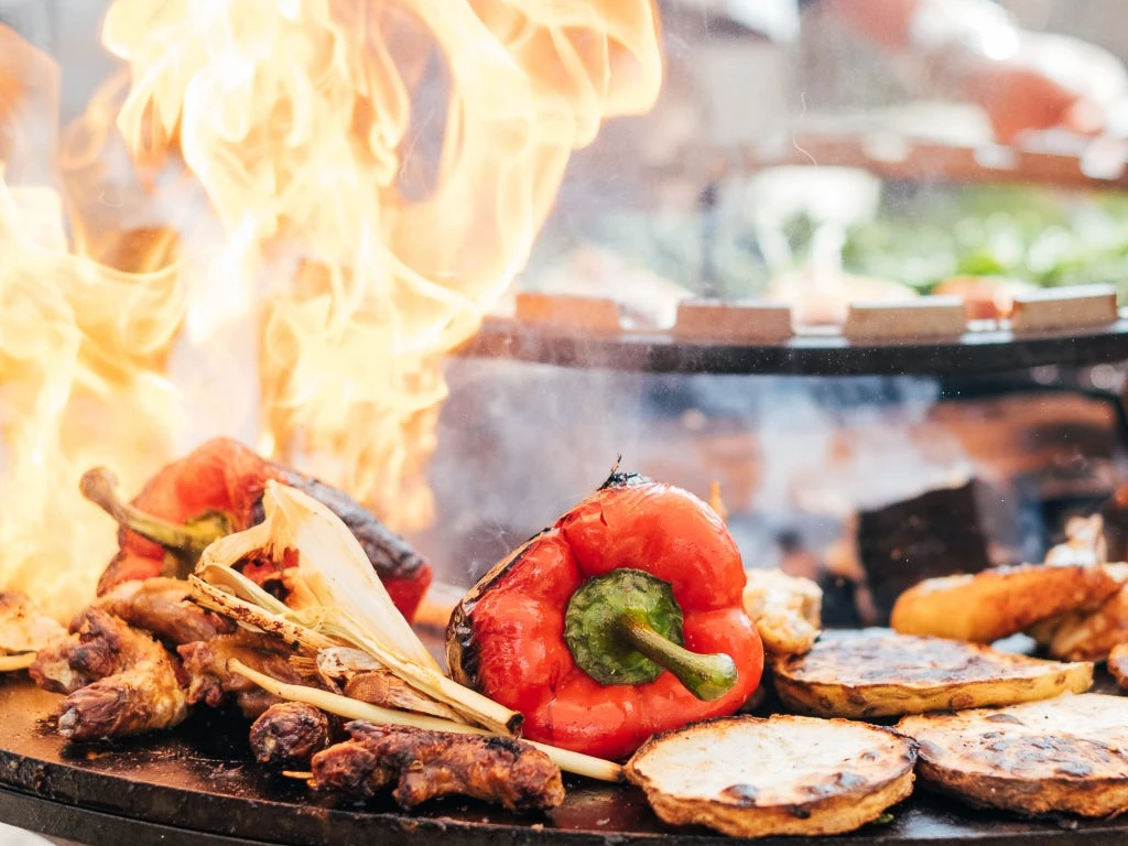 Monheim am Rhein'deki Marienburg'daki Grill Academy Kırmızı biber ve soğan gibi çeşitli sebzeler büyük bir ızgarada ateşte kavruluyor.