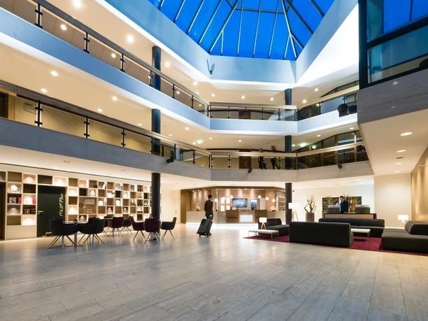 Lobby hotelu Best Western Plus Parkhotel w Velbert Przestronne lobby hotelowe z jasną marmurową podłogą, nowoczesnymi miejscami do siedzenia i szklanym sufitem.