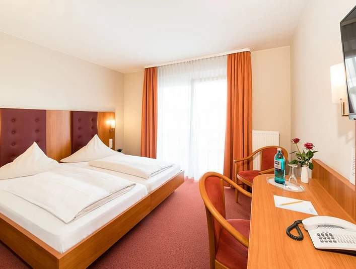 Pokój hotelowy w hotelu-restauracji Zum Vater Rhein w Monheim am Rhein Pokój hotelowy z dwoma pojedynczymi łóżkami, biurkiem, telewizorem z płaskim ekranem, zasłonami świetlnymi i czerwonym wystrojem.