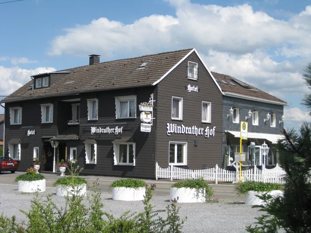 Hotel restaurante Windrather Hof en Velbert Un edificio tradicional con entramado de madera, marcos de ventanas blancos y carpintería detallada.