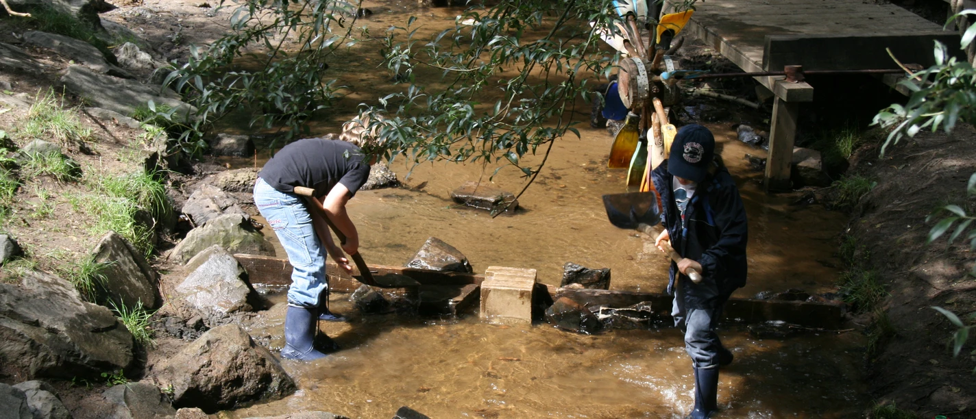 Costruzione di una diga nel parco giochi di Hilden I bambini giocano lungo il ruscello e costruiscono una piccola diga con le pietre in un parco giochi avventura.