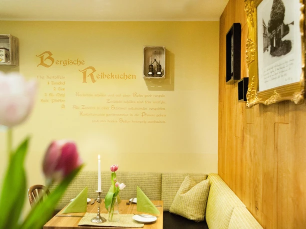 Room in the Landhotel Napoleon with a set table, candle, tulips and a recipe on the wall