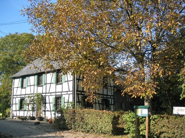 nederzetting Hofferhof Vakwerkhuis in een herfstachtige omgeving met loofbomen en een pad op de voorgrond.