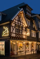 Hirsch Restaurant_Façade.jpg Maison à colombages avec façade illuminée, restaurant "Hirsch", éléments traditionnels, photographiés le soir.