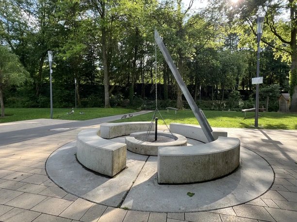 Vrij toegankelijke barbecueplaats in Wiehlpark Moderne zonnewijzer van metaal en betonnen banken in een groen park in de zon.