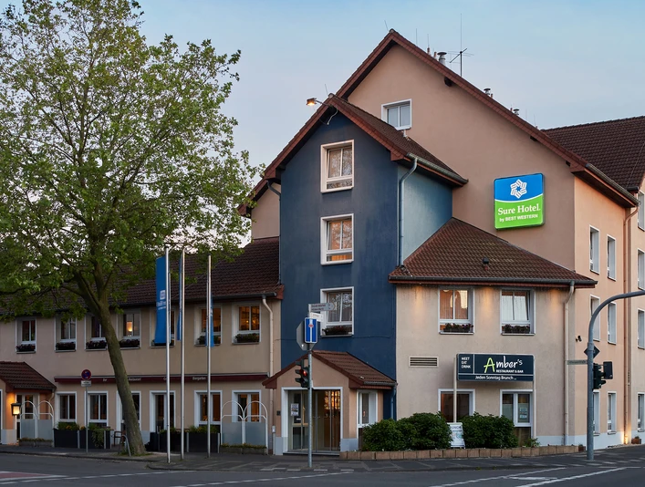 Sure Hotel sieci Best Western Hilden-Düsseldorf Sure Hotel by Best Western w Hilden-Düsseldorfie, na rogu ulicy, w sąsiedztwie rośnie drzewo.