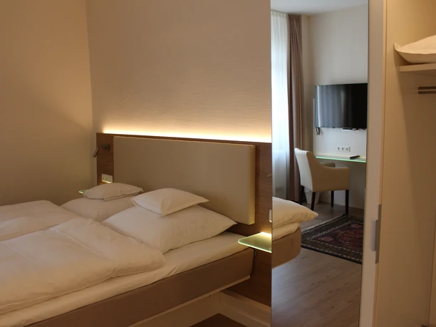 Habitación doble en el hotel Stüttgens en Velbert Habitación doble amueblada de forma moderna con una cómoda cama, escritorio, TV y armario.
