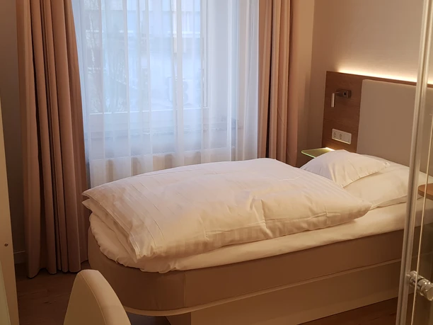 Habitación individual en el hotel Stüttgens de Velbert Una habitación individual con cama, TV, ventana, escritorio, silla y un baño moderno.