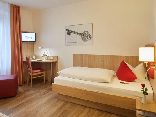 Pokój jednoosobowy w hotelu zur Traube w Velbert Pokój jednoosobowy w hotelu Hotel zur Traube w Velbert, wykończony w drewnie, wyposażony w łóżko, biurko i mały telewizor.