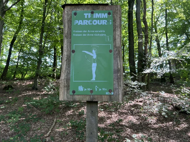 Fitness pad Houten bord in het bos met een beschrijving van een armoefening voor een fitnessparcours.