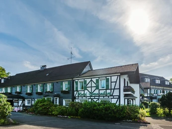 Exterior view of Lohmanns Romantik Hotel Gravenberg in Langenfeld Half-timbered building of Lohmann's Romantik Hotel Gravenberg in Langenfeld with green accents under a blue sky.