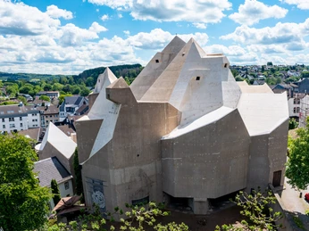 Panoramiczny widok na Neviges Mariendom Monumentalna betonowa architektura Mariendom Neviges, otoczona miejskim krajobrazem.