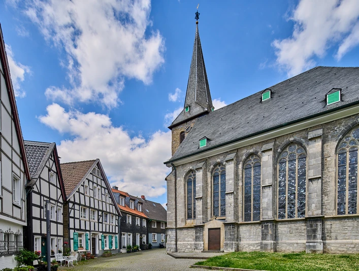 Centre-ville historique avec place de l'église à Wülfrath Place de l'église de Wülfrath avec une église impressionnante et des maisons à colombages traditionnelles sous un ciel bleu.