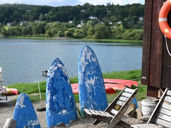 Chaises et anciennes planches de surf au premier plan et Edersee en arrière-plan